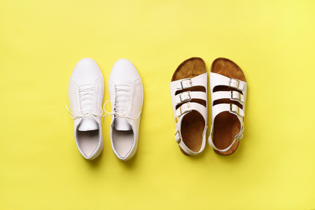 Summer female shoes - sandals (birkenstock) and leather sneakers on yellow background with copy space. Top view. Minimal flat lay. First step, selection conceptの写真素材