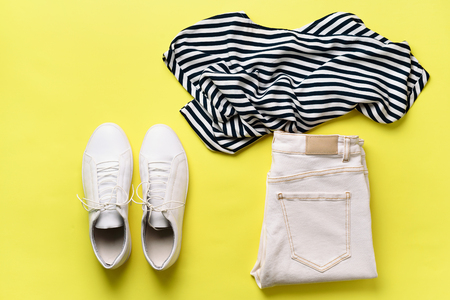 Female white sneakers and jeans, striped t-shirt on yellow background with copy space. Top view. Summer fashion, capsule wardrobe concept. Creative flat layの写真素材