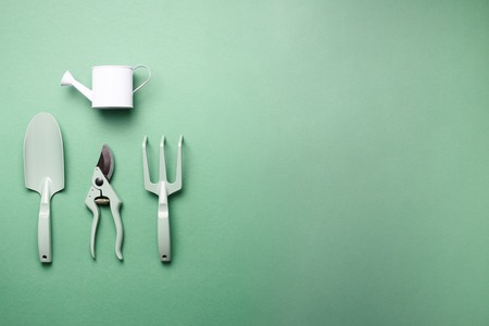 Gardening tools and utensils on green background. Top view with copy space. Pruner, rake, shovel, watering can for garden manteinance. Summer season. Farming, landscaping concept.の写真素材