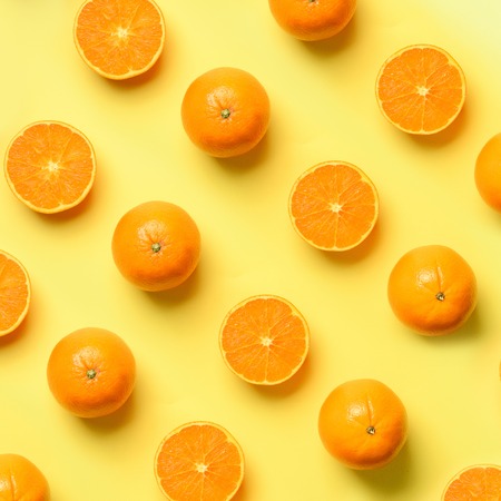 Fruit pattern of fresh orange slices on yellow background. Top view. Copy Space. Pop art design, creative summer concept. Half of citrus in minimal flat lay style. Square crop.の写真素材