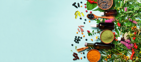 Holistic medicine approach. Healthy food eating, dietary supplements, healing herbs and flowers. Turmeric, dried lavender, spirulina powder in wooden bowls, fresh berries, omega acid capsules.の写真素材