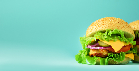 Fast food banner. Juicy meat burger, french fries potatoes and cola drink on blue background. Take away meal. Unhealthy diet concept with copy space.の写真素材