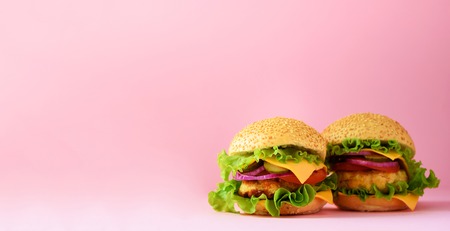 Fast food banner. Juicy meat burger with beef, cheese, lettuce, onion, tomatoes on pink background. Take away meal. Unhealthy diet concept and copy space.の写真素材