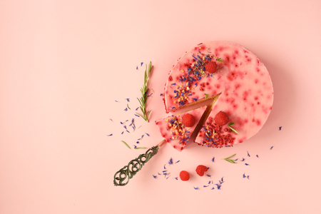 Delicious raspberry cake with fresh berries, rosemary and dry flowers on pink background. Copy space for your text. Vegetarian, vegan food concept.の写真素材
