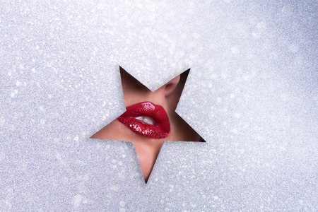 Beauty salon advertising banner with copy space. View of bright lips with glitter through hole in silver paper background. Make up artist, beauty concept. Ready to new year party. Cosmetics saleの写真素材
