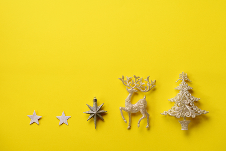 Festive silver dear, stars, fir-tree, cone on yellow backgroundの写真素材