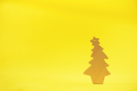 Wooden Christmas tree on yellow background with copy space. New Year party. Winter holiday concept....