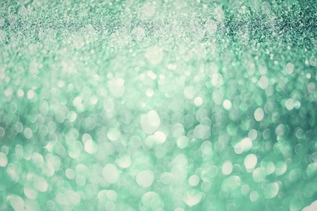 Green abstract bokeh lights. Shiny glitter background with copy space. New year and Christmas concept. Sparkling greeting card.の写真素材