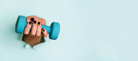 Woman hand holding blue dumbbell on blueの写真素材
