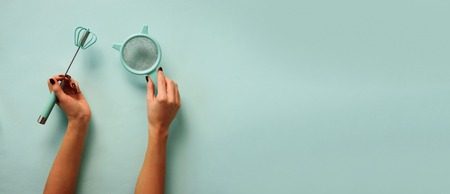 Woman hand holding kitchen utensils on blueの写真素材