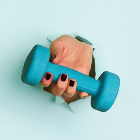 Woman hand holding blue dumbbell on blueの写真素材