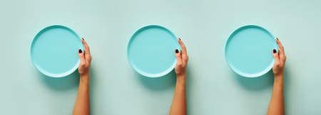 Female hand holding empty blue plate on pastel  with copy space. Healthy eating, dieting concept. Banner.の写真素材