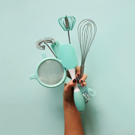 Baking flat lay. Female hands holding kitchen tools, sieve, rolling pin, spatulaの写真素材