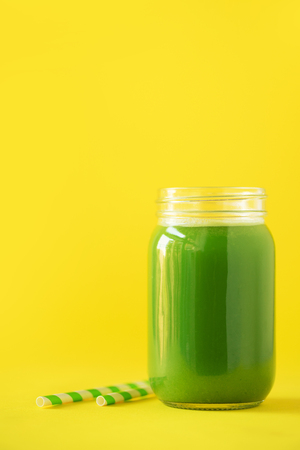Bottle of green celery smoothie on yellowの写真素材