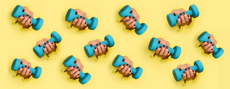Chaotic pattern of female woman hand holding blue dumbbell on yellowの写真素材