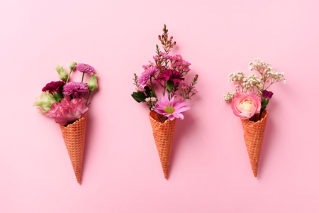 Summer minimal concept. Ice cream cone with pink flowers and leaves on punchy pastelの写真素材