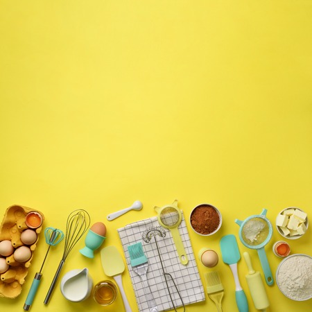Square crop. Baking ingredients - butter, sugar, flour, eggs, oil, spoon, rolling pin, brush, whisk, towel over yellow background. Bakery food frame, cooking concept. Top view, copy space. Flat lay.の写真素材