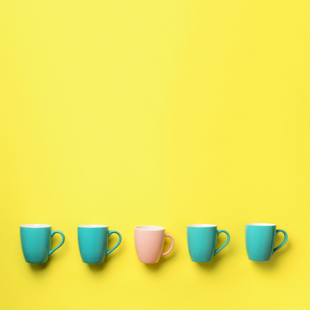 Pattern from blue and pink cups over yellow background. Square crop. Birthday party celebration, baby shower concept. Punchy pastel colors. Minimalist style design.の写真素材