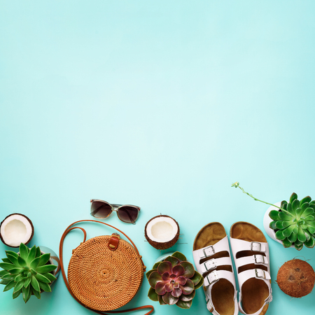Stylish rattan bag, coconut,  succulent, sunglasses on blue background. Banner. Top view with copy space. Trendy bamboo bag and white shoes. Summer fashion flat lay.の写真素材