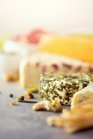 Assortment of hard, semi-soft and soft cheeses with olives, grissini bread sticks, capers, grape, on grey concreteの写真素材