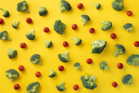 Creative layout of fresh broccoli, tomatoes on yellow paper background. Top view. Food pattern in minimal style. Flat lay. Banner.の写真素材