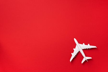 White plane, airplane on red color background with copy space. Top view, flat lay. Minimal style design. Travel, vacation concept.の写真素材