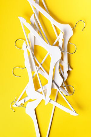White clothes hangers on yellow background with copy space. Flat lay. Top view. Minimalism style. Creative layout. Fashion, store sale, shopping concept. Banner for feminine blog.の写真素材