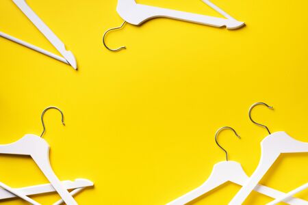 Top view of white clothes hangers on yellow background with copy space. Flat lay. Minimalism style.の写真素材