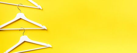 Top view of white clothes hangers on yellow background with copy space. Flat lay.の写真素材