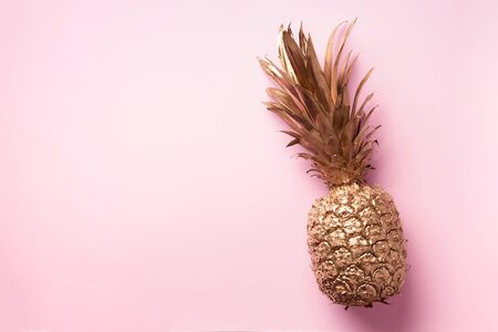 Creative layout. Gold pineapple on pink background with copy space. Top view. Tropical flat lay. Exotic food concept, crazy trend.の写真素材