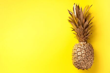 Creative layout. Gold pineapple on yellow background with copy space. Top view. Tropical flat lay. Exotic food concept, crazy trend. Banner.の写真素材