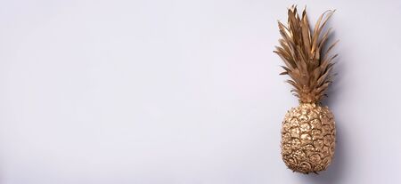 Creative layout. Gold pineapple on grey background with copy space. Top view. Tropical flat lay. Exotic food concept, crazy trend. Banner.の写真素材