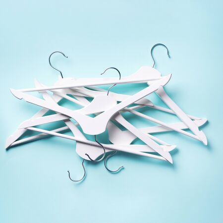 White clothes hangers on blue background with copy space. Flat lay. Top view.の写真素材