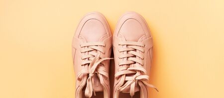 Woman fashion pink shoes on pink background with copy space. Top view. Flat lay. Fitness, sport concept. Nude female sneakers.の写真素材