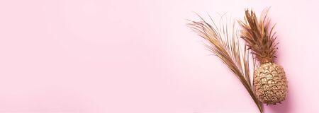 Creative layout. Gold pineapple and golden palm on pink background with copy space. Top view....