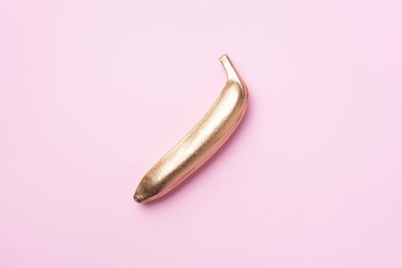 Golden banana on pink background. Creative food concept. Top view. Flat lay. Single exotic gold fruitの写真素材