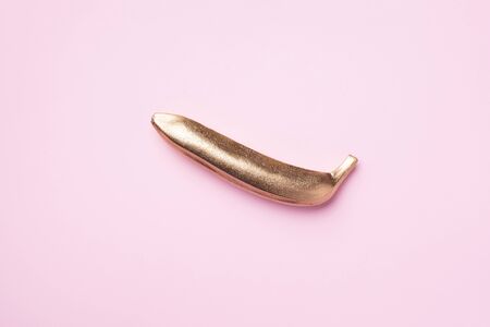 Golden banana on pink background. Creative food concept. Top view. Flat lay. Single exotic gold...