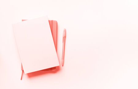 Top view of open notebooks on trendy coral color background. Copy space. Woman business, study, back to school concept. Time managenet, to do list. Banner.の写真素材