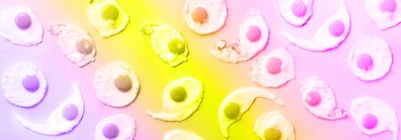 Fried eggs or scrambled eggs pattern in trendy neon colors. Rainbow gradient background with copy space. Creative food concept. Top view. Banner.の写真素材