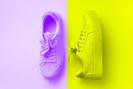 Woman fashion pink shoes on trendy neon yellow and violet colors background with copy space. Top view. Flat lay. Fitness, sport concept. Nude female sneakers.の写真素材