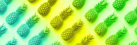 Fresh pineapples on vibrant rainbow gradient background. Top View. Pop art design, creative concept. Copy Space. Neon pineapple pattern for minimal styleの写真素材