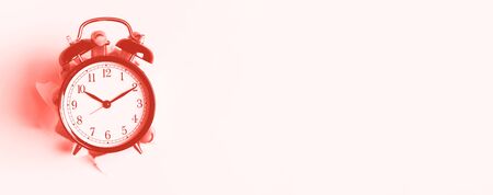 Hand holding black alarm clock through hole in trendy coral color background. Wake up alert concept....