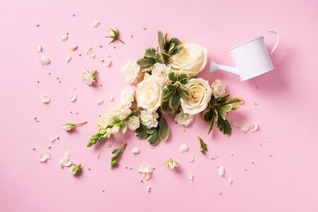 Watering can and white rose flowers, petals over pink background. Ideas for creative business. Summer, spring or gardening conceptの写真素材