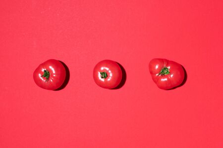 Red tomatoes pattern on red background. Flat lay, top view. Summer minimal concept. Vegan and vegetarian diet.の写真素材