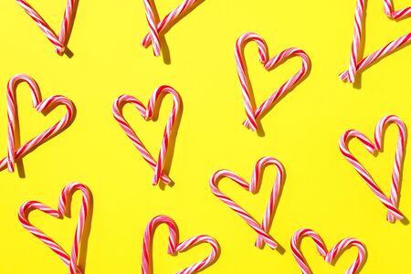 Pattern with hearts made of Christmas candy canes on yellow background. Top view. Flat lay. Love,...