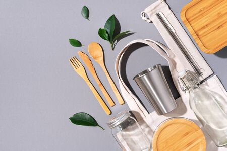 Cotton bags, glass jar, bottle, metal cup, straws for drinking, bamboo cutlery and boxes on gray background. Sustainable lifestyle. Zero waste, plastic free shopping conceptの写真素材