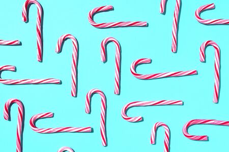 Pattern of Christmas candy cane on blue background. Top view. Flat lay. Creative minimal concept. Greeting card on Christmas and New Year. Art compositionの写真素材