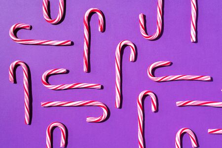 Pattern of Christmas candy cane on violet background. Top view. Flat lay. Creative minimal concept....