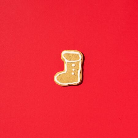 Festive handmade cookies on red background. Gingerbread boot shapes. New year and Christmas concept.の写真素材