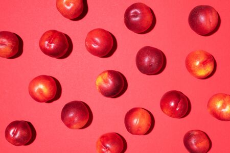 Nectarines pattern on red background. Frame made of fresh fruits. Flat lay, top view, copy space. Vegan and vegetarian diet.の写真素材
